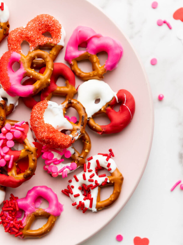 top down view of Valentine's day pretzels coated with pink, white and red melted candy on a pink plate
