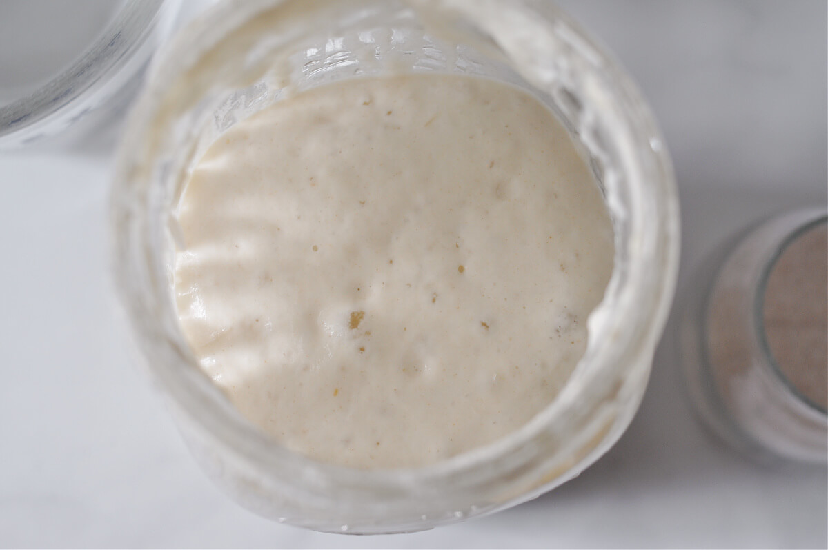Jar of sourdough starter with bubbles on the top of the starter.