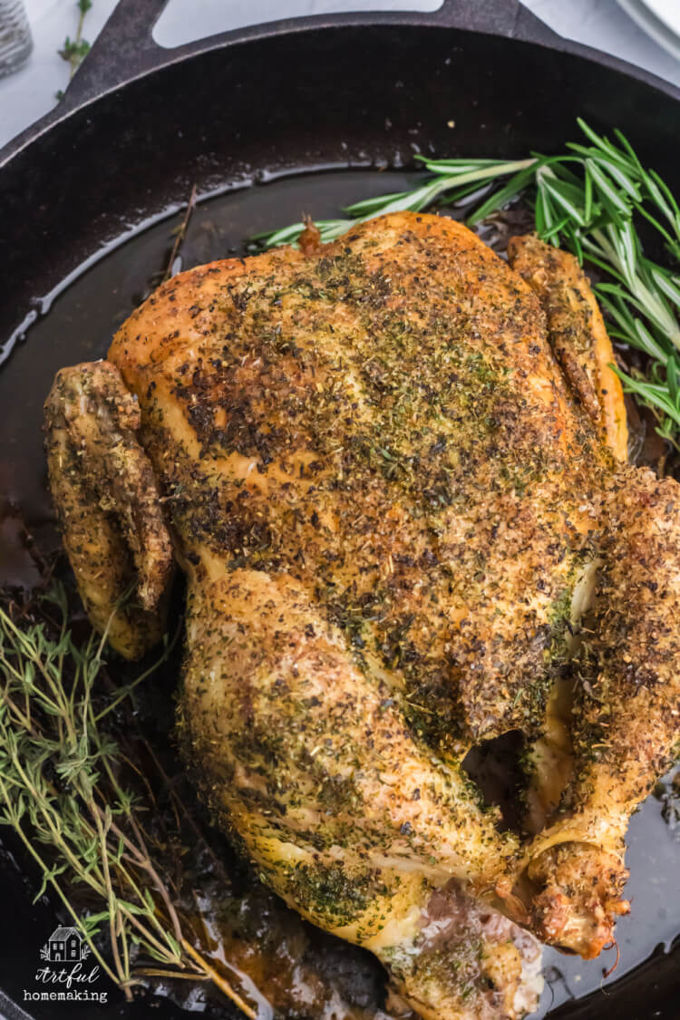 baked chicken in cast iron skillet with herbs and seasonings on it